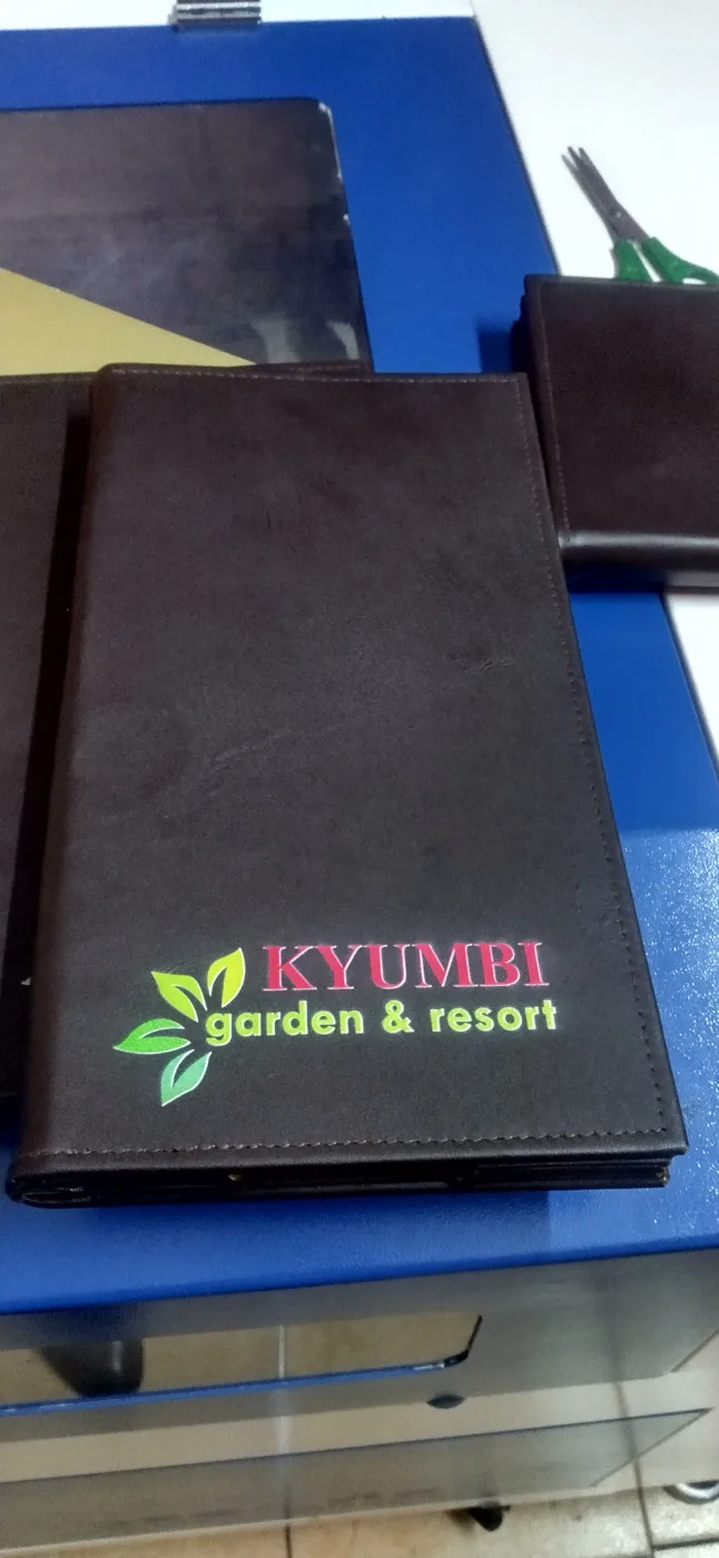 Single branded menu folder open on the bench showing the stitched edge and foil logo