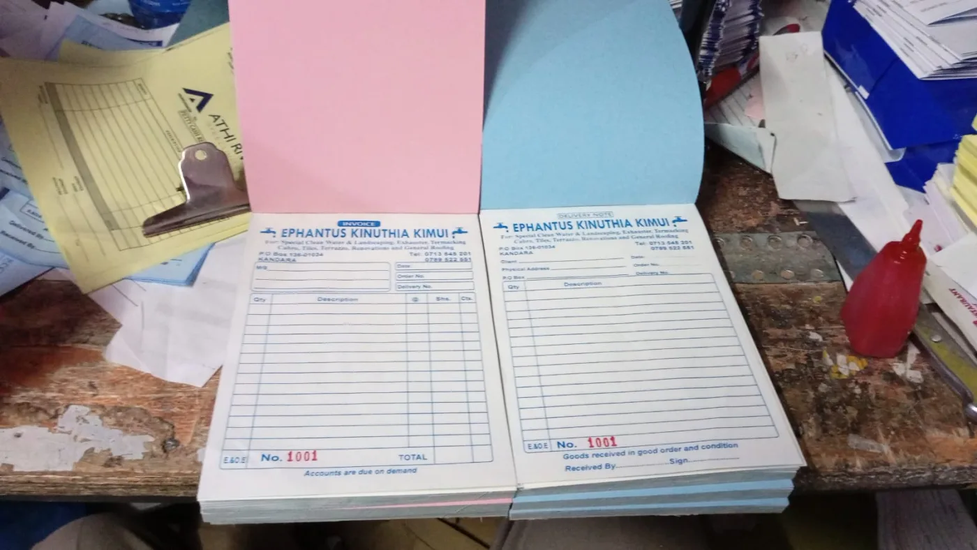 Carbonless duplicate receipt books open on the bindery bench during finishing