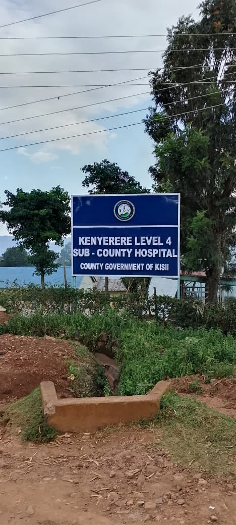 Post-mounted roadside signboard for a county facility, set in concrete