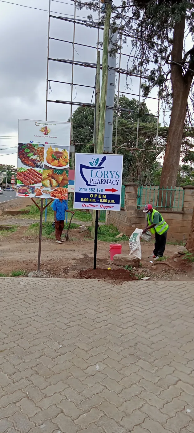Pair of pole-mounted roadside signs for a pharmacy, seen from the walkway